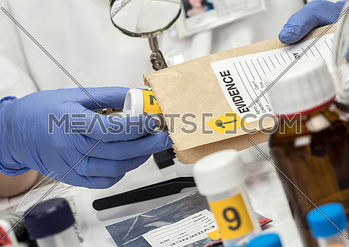 Police specialized taking sample of hair of a bag of evidence in forensic laboratory, conceptual image