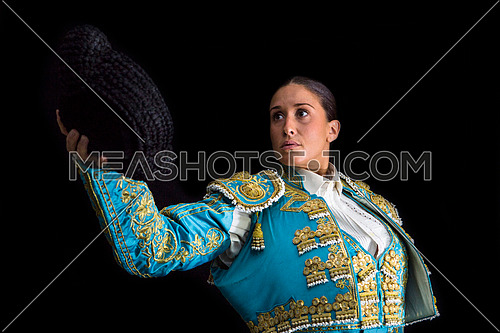 Woman bullfighter salutes with his montera in black background