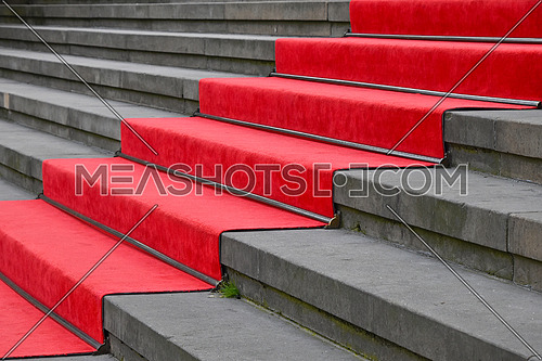 Close up red carpet over grey concrete stairs perspective ascending, low angle side view