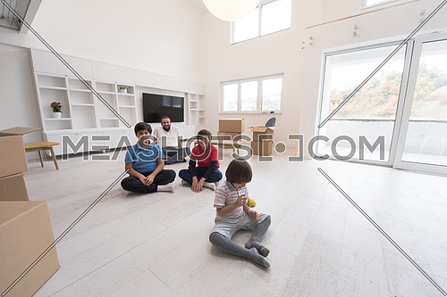 portrait of happy young boys with their dad sitting on the floor in a new modern home