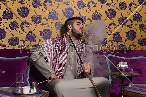 Muslim Man Smoking Turkish Hookah In The Cafe With Colorful Walls On Background