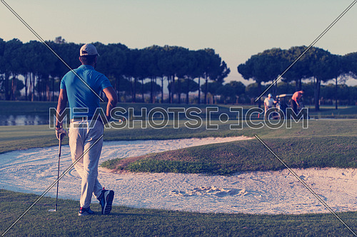 golfer  from back looking to ball and  hole in distance, handsome middle eastern golf player portrait from back with beautiful sunset in background