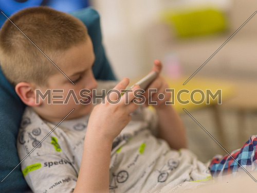 little boy playing video games on smartphone at home