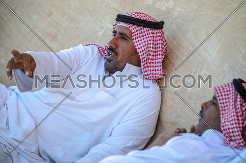 med-shot for Two Bedouin males wearing traditional clothing while resting and talking in Sinai by day.