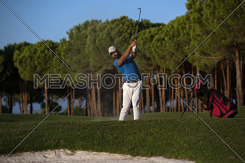 golfer shot ball from sand bunker at golf course with beautiful sunset in background