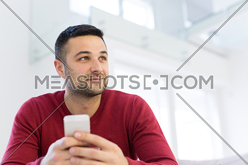 Handsome casual young man using a mobile phone at  home