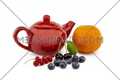 Colorful red teapot and assorted berries including blueberries, cherries, red currants and orange over white in a concept of fruit tea