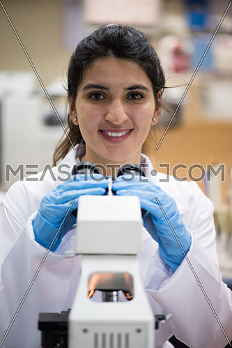 portrait of a young middle eastern woman with a microscope in a large modern laboratories