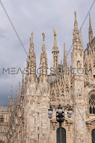 Details of Duomo with the golden statue name "Madonnina" on the top,overcast sky.