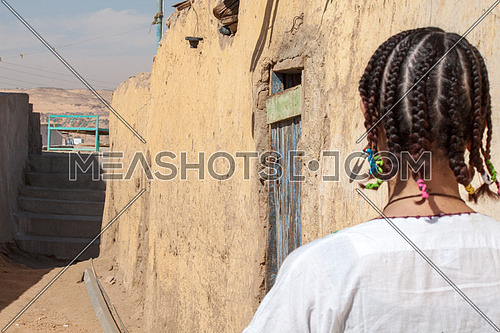 A nubian girl from behind standing in an alley