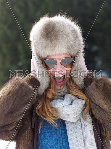 portrait of beautiful young redhair woman in snow scenery with warm hat
