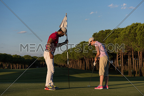 male golf instructor teaching female golf player, personal trainer giving lesson on golf course
