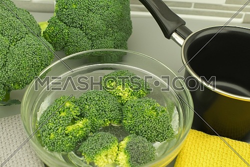 Fresh broccoli florets soaked in a clear bowl of water. Selective focus shot