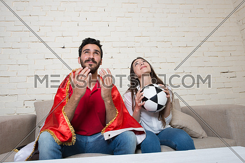 A young couple watching football match in living room