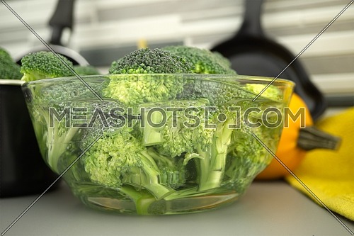 Fresh broccoli florets soaked in a clear bowl of water. Selective focus macro shot