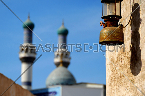 oil lantern hanged on the wall with mosque in the background