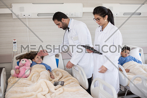 arabian mischievous and beauty kid get treatment by young doctors in modern hospital room