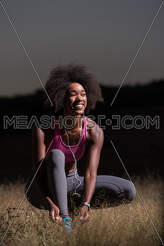 young African american woman runner tightening shoe lace in nature  Fitness, people and healthy lifestyle