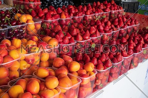 basket of red ripe strawberries and apricots for sale in the steet shop.