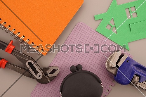 House ownership, building or construction still life concept with a flat lay of notebooks, wrench, purse, pencil and colorful cutout paper homes