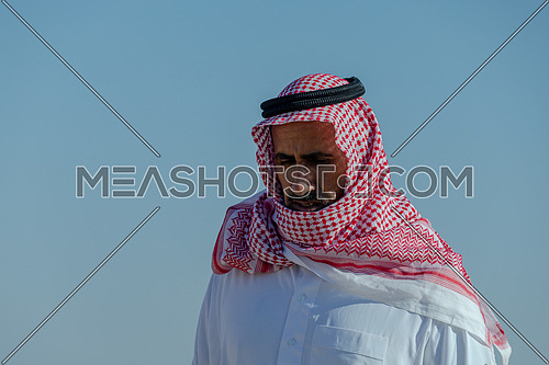Portrait for bedouin male climbing down rocks at day.