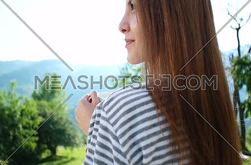 woman drinking coffee in front of luxuary villa