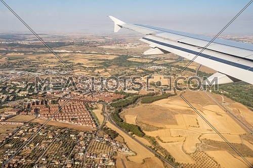 Looking through aircraft window during flight. Aircraft wing over blue skies and cityscape .Copy space.