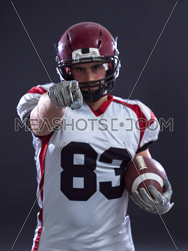 Portrait of American football player pointing against gray background