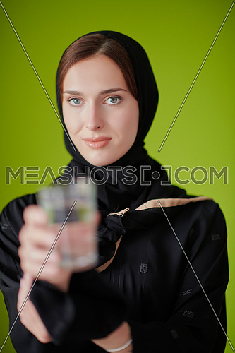 Modern muslim woman in abaya holding a glass of water in front of her. Arab girl representing iftar time, Ramadan kareem concept