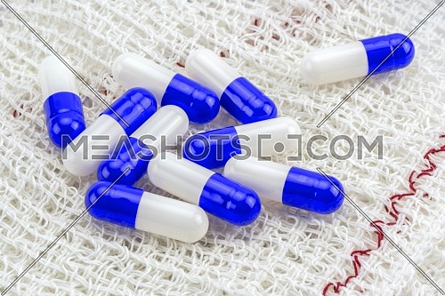 Some white and blue pills wrapped in gauze, conceptual image