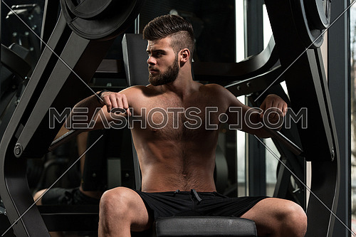 Handsome Man Is Working Out Chest On Machine In A Modern Gym