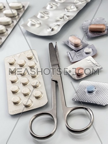 Different types of medications with scissors in a hospital, conceptual image