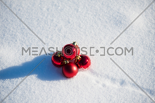 christmas red balls with long shadows  in fresh snow on beautiful sunny winter day