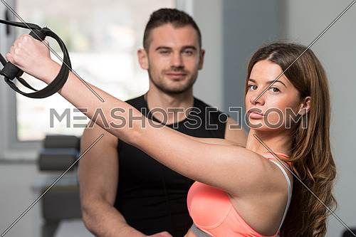 Personal Trainer Showing Young Woman How To Train With Trx Fitness Straps In A Gym