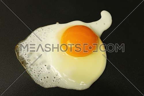 Close up cooking one sunny side fried egg on electric grill surface, high angle view