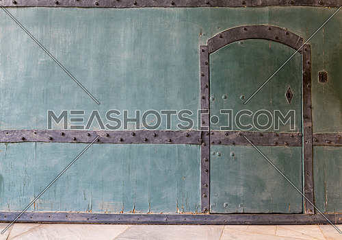 Closed wooden blue door in a wooden blue wall and marble floor