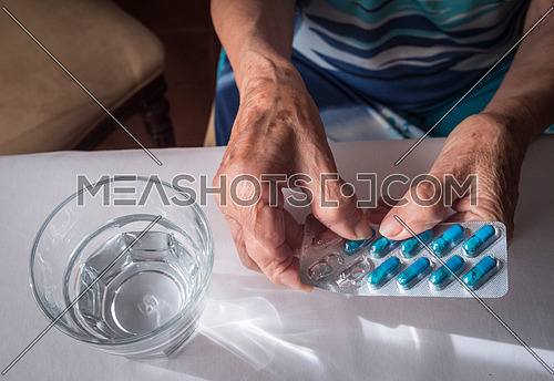 Oldster taking daily medication dose at home, Andalusia, Spain