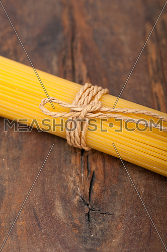 Italian pasta spaghetti tied with a rope on a rustic table