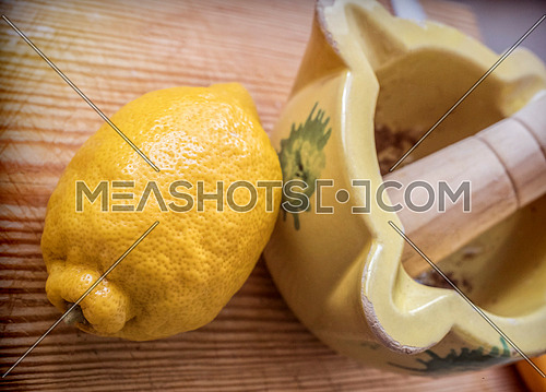 Traditional ceramic mortar next to a lemon in a kitchen, traditional cooking utensils