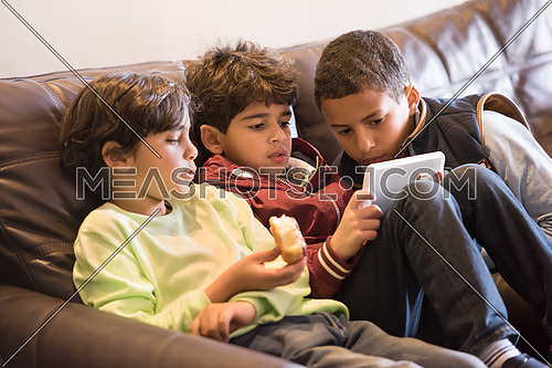 Young middle eastern boys are having fun with the tablet in the living room