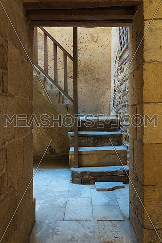 Ancient external old bricks stone wall and doorway revealing a stone staircase with wooden balustrade, Old Cairo, Egypt