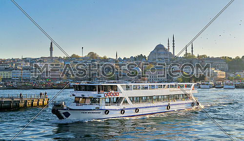 Istanbul, Turkey - April 25, 2017: City view of Istanbul, Turkey from the sea overlooking a passing ferry with Eminonu district and Sulaymaniye Mosque in the background