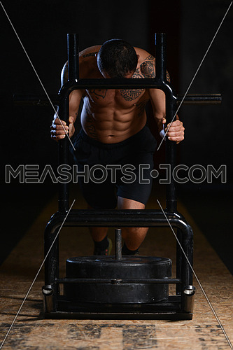 Muscular Man Doing Heavy Weight Exercise Weighted Speed Sled In Gym