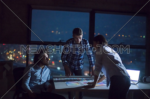 young team of business people in group, architect and engineer on construction site checking documents and business workflow using laptop computer in new startup office at night