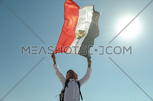 Bedouin man holding Egyptian Flag in Sinai Trail from Ain Hodouda at day.