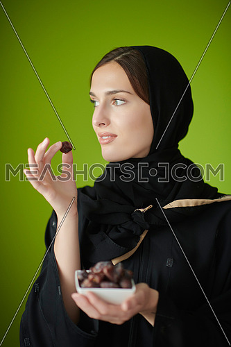 Young muslim girl wearing traditional muslim clothes holding dried dates. Arab girl representing iftar time, holy fasting month, Ramadan Kareem