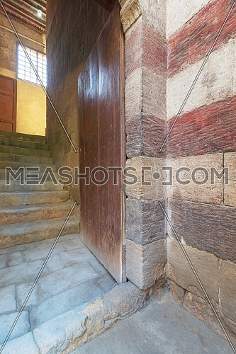 Open grunge wooden door revealing old stone staircase going up leading to Bayt al Razzaz, a Mamluk era historic building, Cairo, Egypt