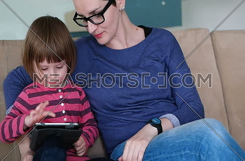Mother teaches daighter how to use digital tablet