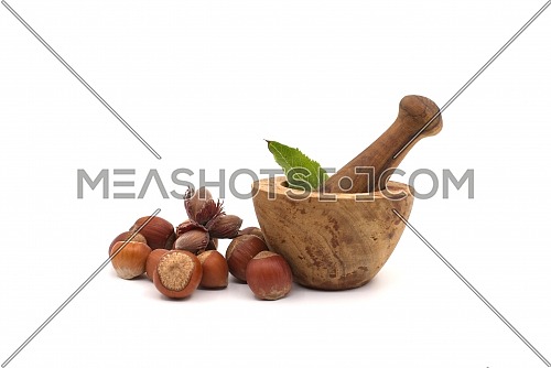 Fresh raw hazelnuts and wooden rustic-style mortar and pestle isolated on white background