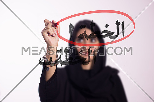 Arabian middle eastern business woman writing with a marker on virtual screen in arabic Plan A & Plan B
isolated on white background